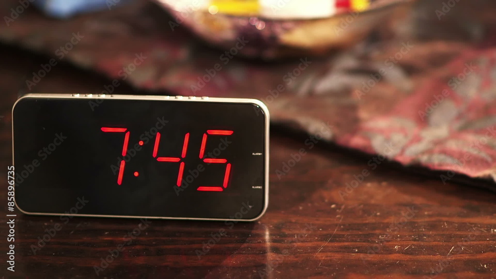 Close-up of a digital clock placed on wooden table when the time's passing.