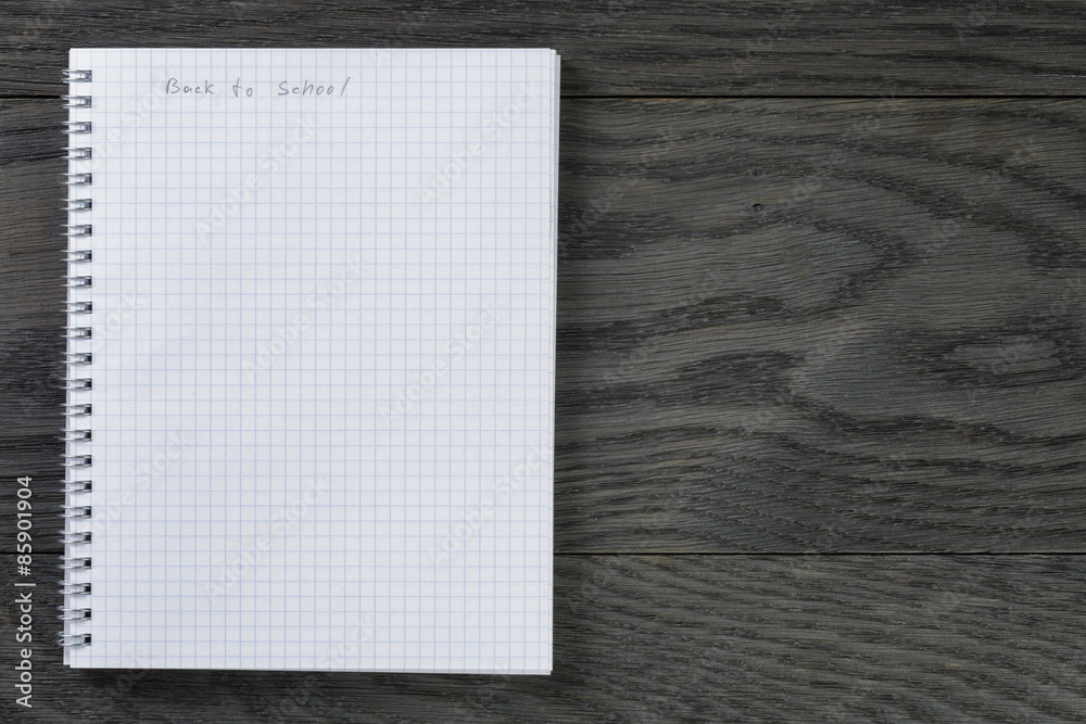 back to school phrase in notepad with chequered pages on gray back to school phrase in notepad with chequered pages on gray