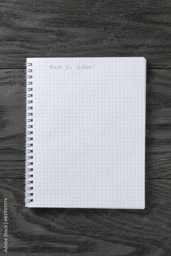 back to school phrase in notepad with chequered pages on gray back to school phrase in notepad with chequered pages on gray