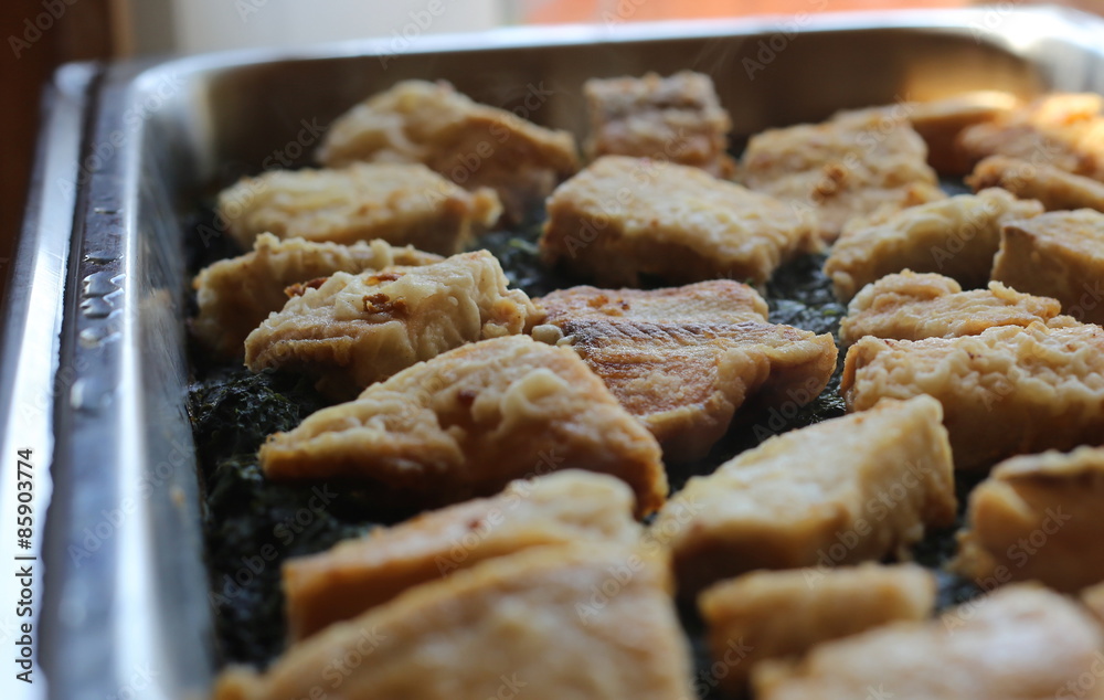 Many fish filets on a spinach bed Many fish filets on a spinach bed