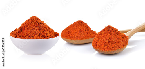 Powdered dried red pepper in a white bowl and wood spoon on whit