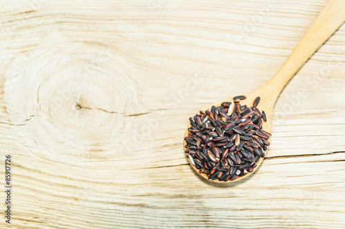 black rice on wooden spoon with wooden background. Product of Th