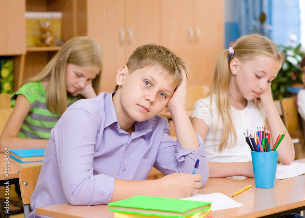 Fototapeta premium tired schoolboy in classroom