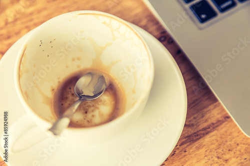 Empty coffee cup and laptop on old wooden table ( Filtered image