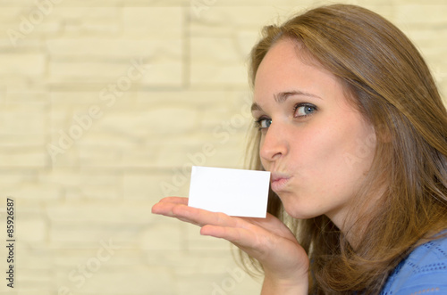 Junge Frau küsst eine Visitenkarte auf ihrer Hand