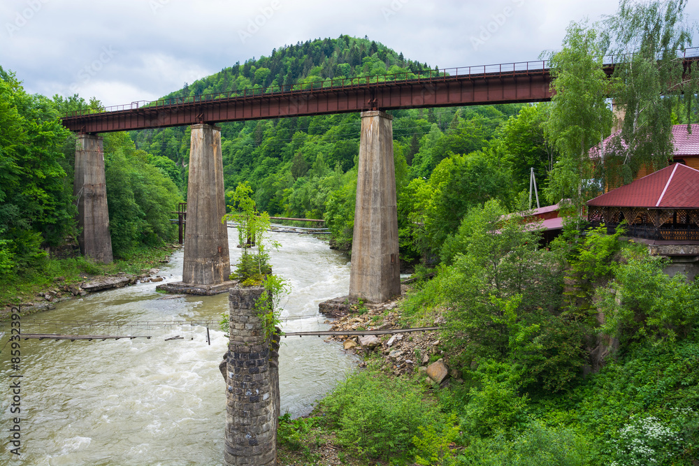 Railway and an old suspension bridge across mountain river