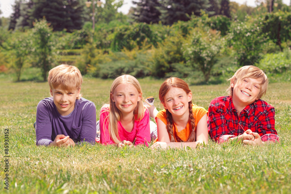 Upbeat children lying on grass in raw Upbeat children lying on grass in raw