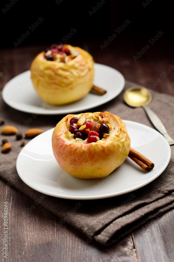 Two stuffed baked apples with oats, cranberries, raisins, almonds and honey on white dessert plates, Christmas sweet Two stuffed baked apples with oats, cranberries, raisins, almonds and honey on white dessert plates, Christmas sweet