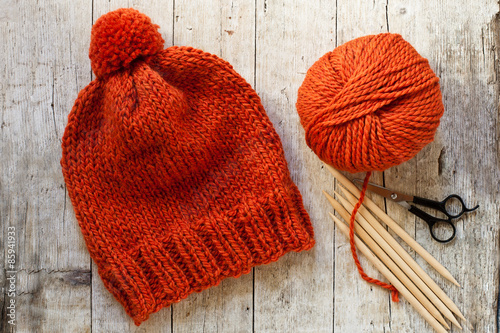 wool orange hat, knitting needles and yarn photo