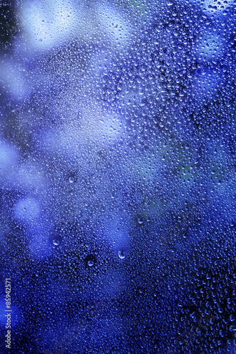 Raindrops on glass  natural blue  background  selective focus