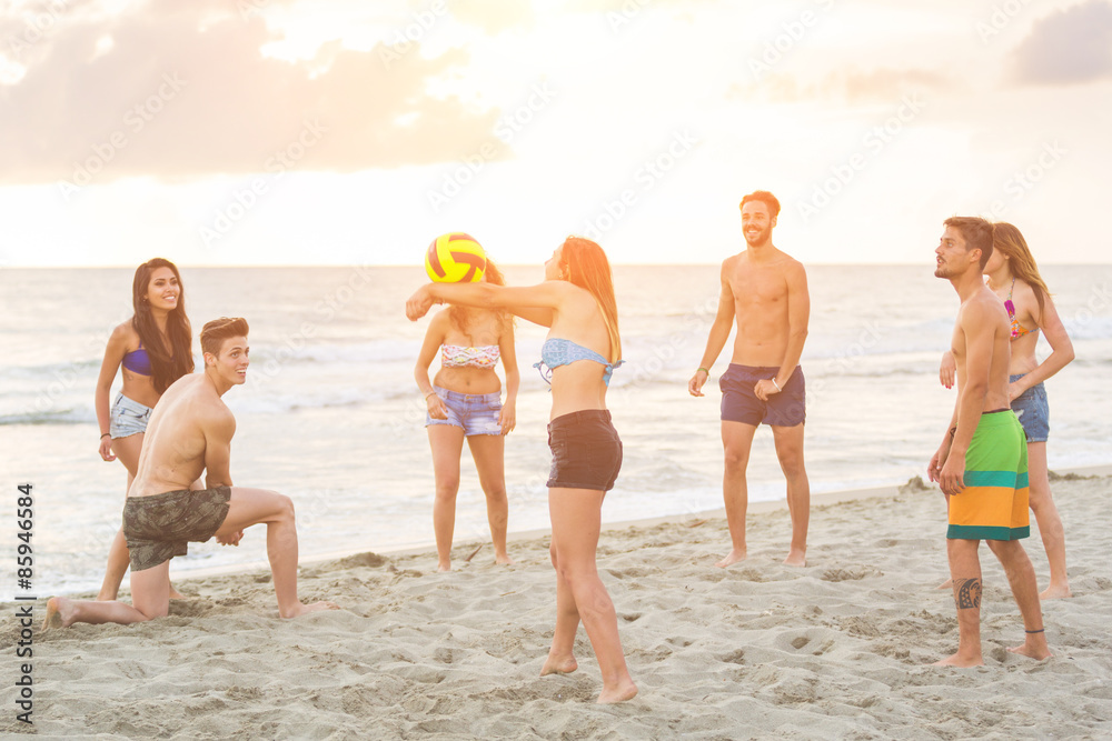 Group of friends playing with ball on the beach