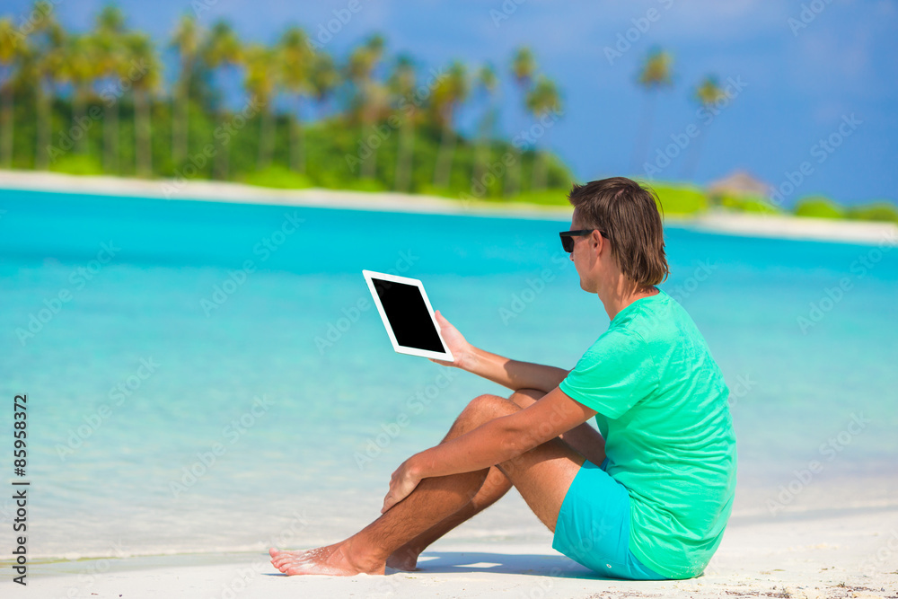 Young man working with laptop at tropical beach