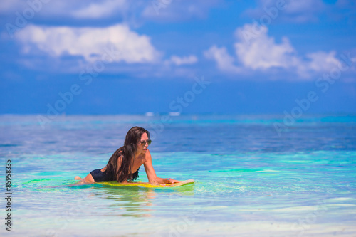 Young slender surf girl at white beach with yellow surfboard
