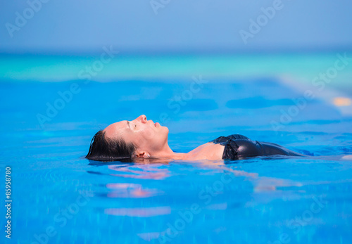 Young woman enjoying water and sun in outdoor swimming pool.