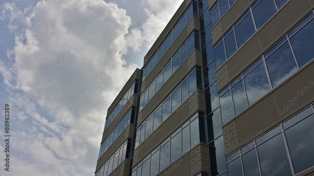 Fototapeta premium modern office building with clouds reflected in windows,front at angle