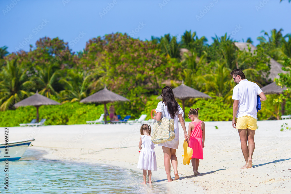 Happy family of four on white beach 