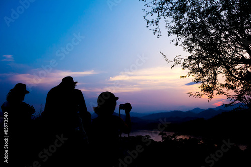 Silhouette of travelers with camera during sunset