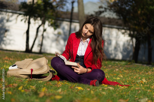 Student girl outside reading book. Caucasian college or universi