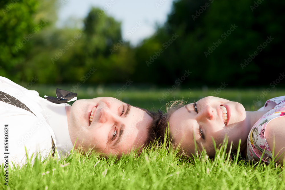 Happy couple in love smiling while lying on summer grass Happy couple in love smiling while lying on summer grass