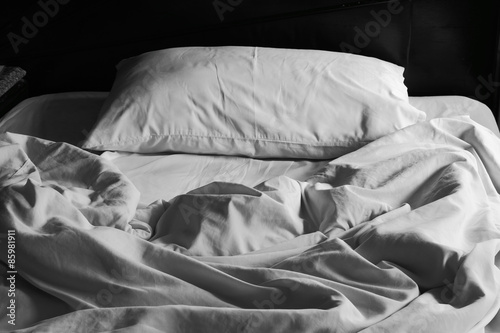 Messy white bed and pillow, in the morning photo