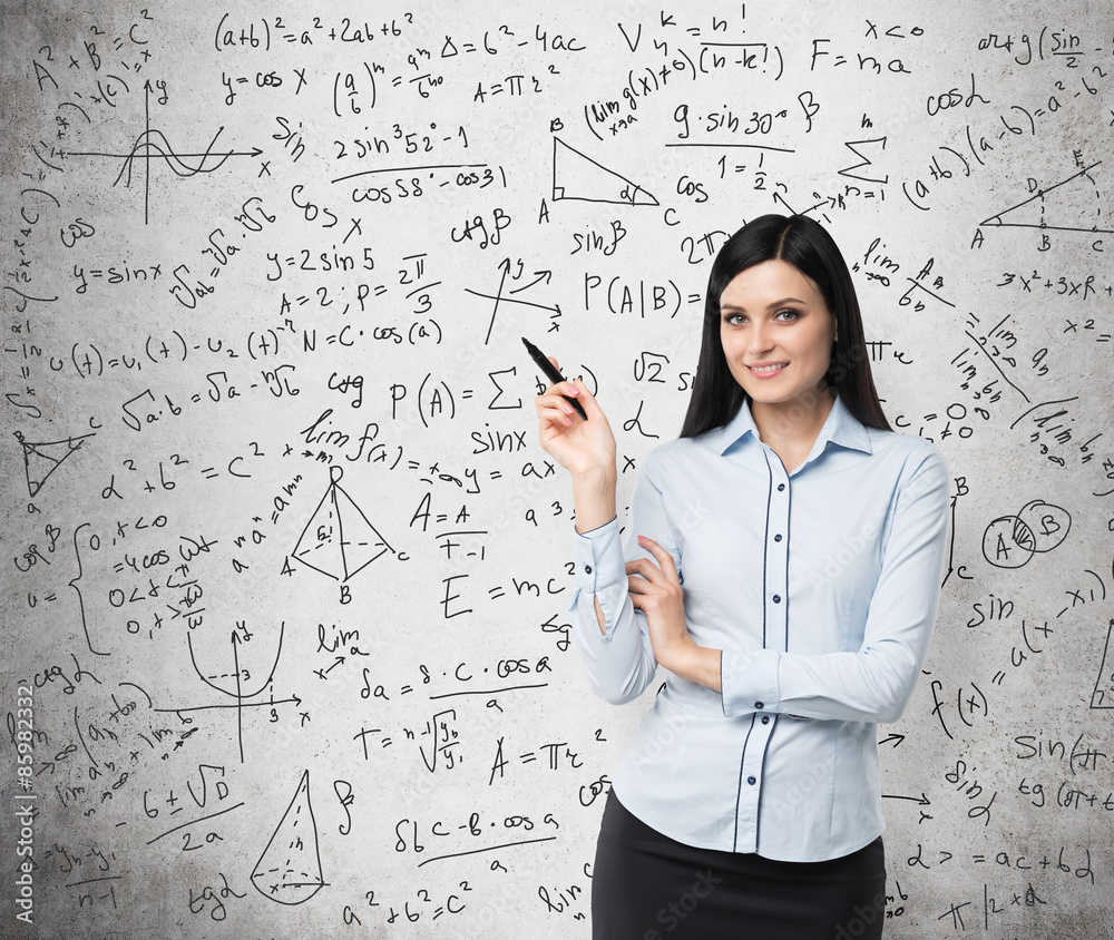 Portrait of smiling woman who points out complicated math calculations. Math formulas are written on the concrete wall. Portrait of smiling woman who points out complicated math calculations. Math formulas are written on the concrete wall.