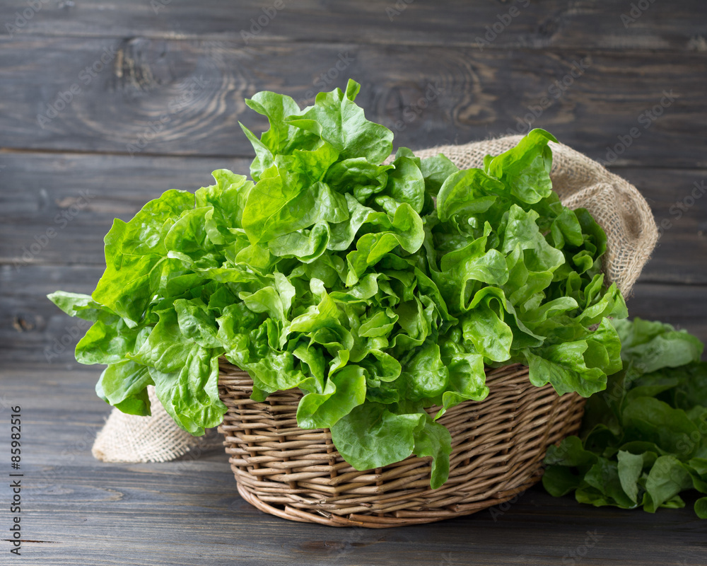 Fresh green organic lettuce in a basket on a wooden rustic background Fresh green organic lettuce in a basket on a wooden rustic background
