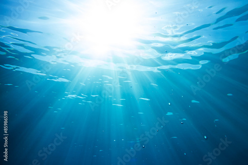 sun and sunbeams shining through the surface of blue ocean water