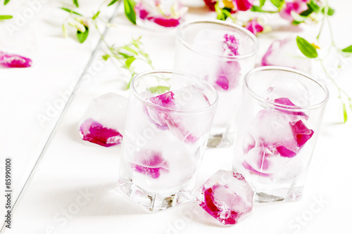 Ice cubes with rose petals on white wooden background, selective © 5ph