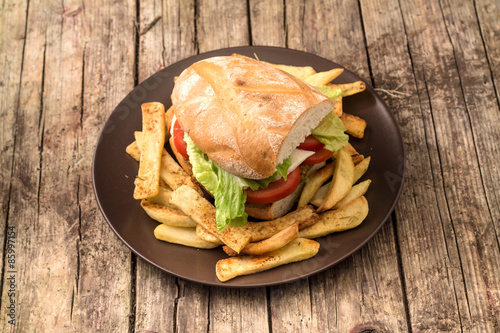 Vegetarian lentil burger in wholewheat bun with lettuce and tomato accompanied by French fries photo