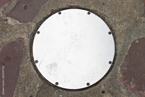 Circle Metal drain cap on sidewalk