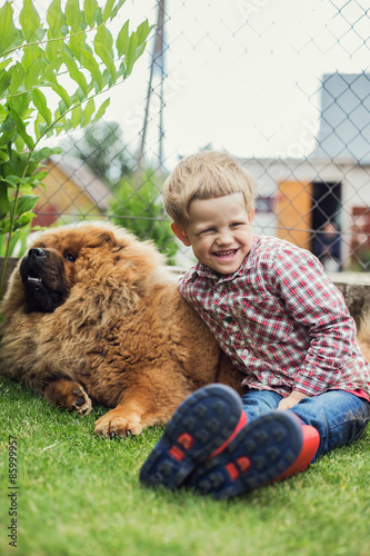 Child lovingly embraces his pet dog. Chow Chow. Outdoor portrait