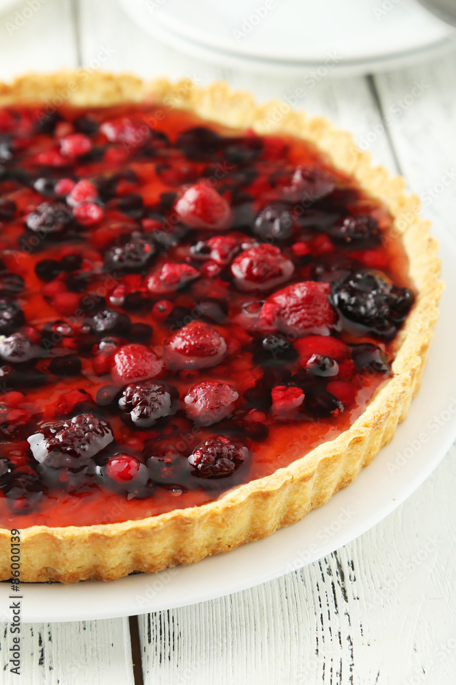 Fresh berry tart on plate on white wooden background Fresh berry tart on plate on white wooden background