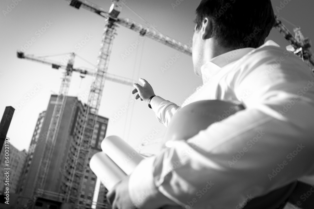 Black and white closeup of engineer pointing at the building Black and white closeup of engineer pointing at the building