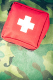 First aid kit on a fabric with camouflage pattern. Toned