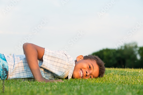 Black boy lying on the grass and smiling.