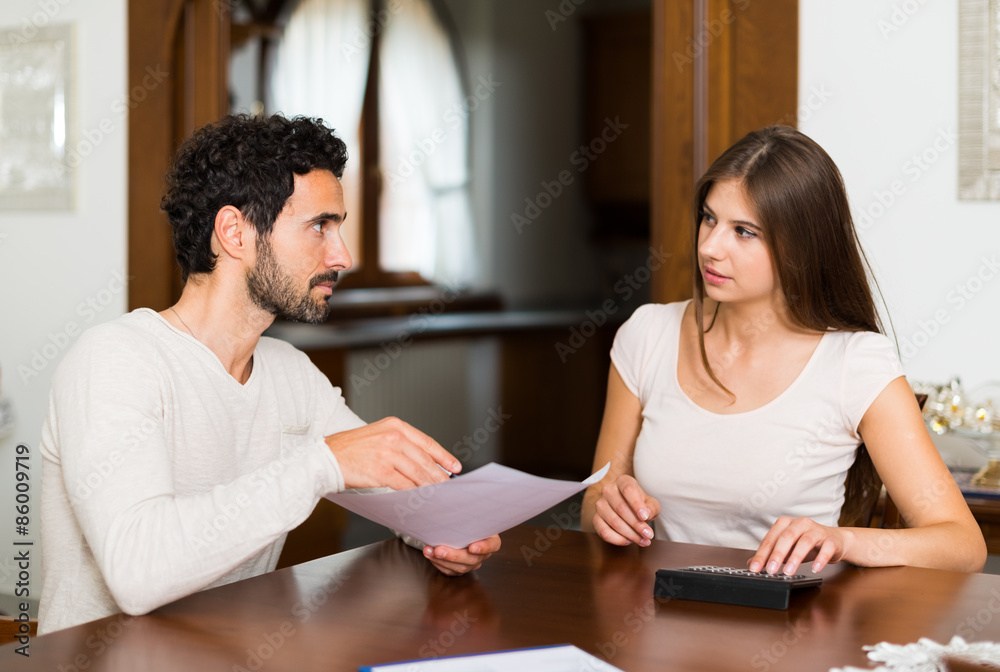 Couple calculating their expenses Couple calculating their expenses