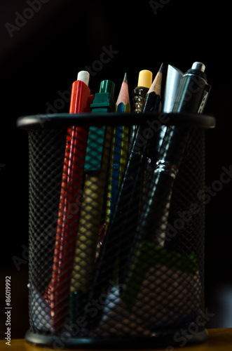 Pens and pencils in a rounded box.