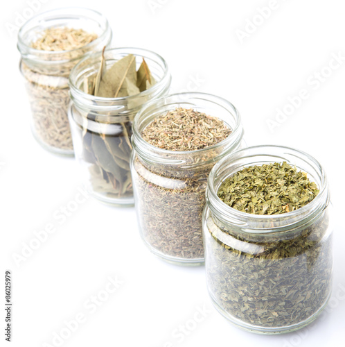 Herbs variety of rosemary, parsley, bay leaves and thyme in mason jars 