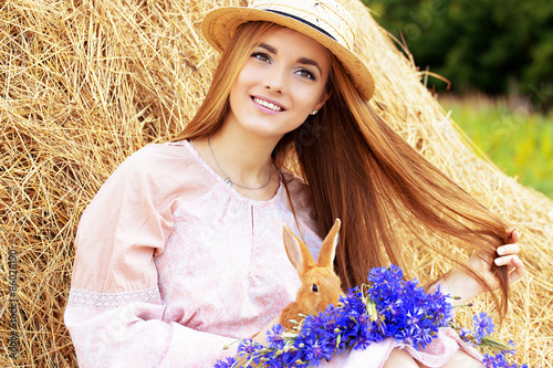 Красивая девушка с длинными волосами на природе с кроликом.
