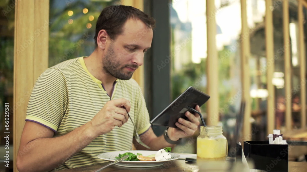 Young man with tablet computer eating salad in cafe
Young man with tablet computer eating salad in cafe