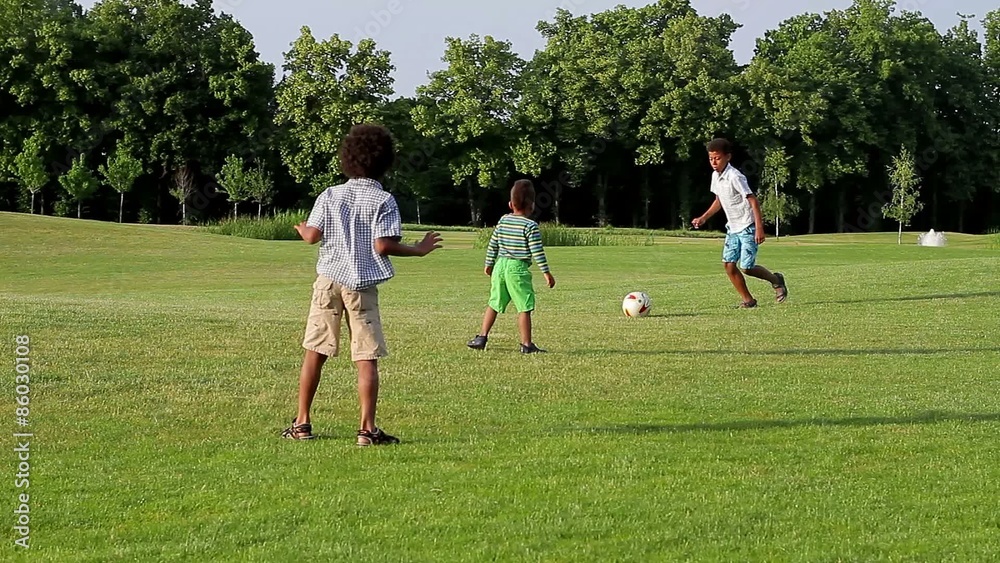 Three children are playing football on the evening glade. Three children are playing football on the evening glade.