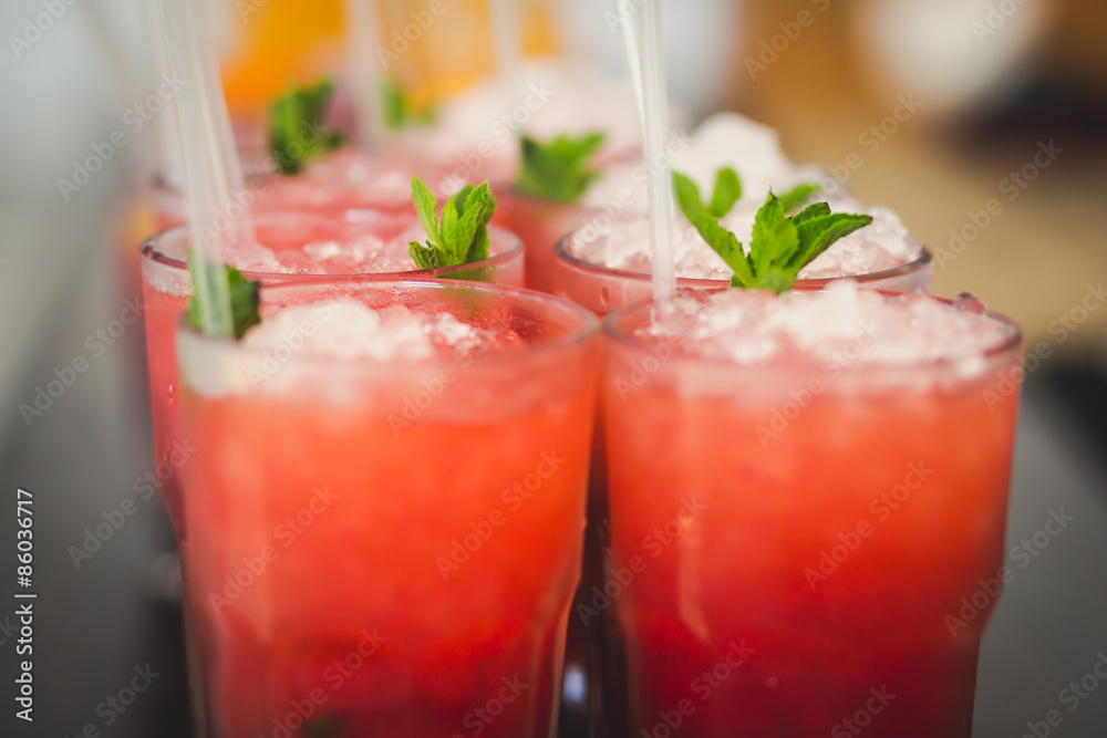 Beautiful line of different colored alcohol mojito cocktails with mint on a open air party, tequila, martini, vodka, and others on decorated catering bouquet table on open air event party. Beautiful line of different colored alcohol mojito cocktails with mint on a open air party, tequila, martini, vodka, and others on decorated catering bouquet table on open air event party.