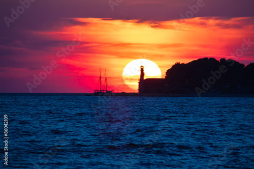 Epic sunset view with lighthouse and saiboat photo