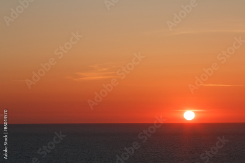 Sunset with the sun about to the set into the Atlantic Ocean. The sun is a full disc 