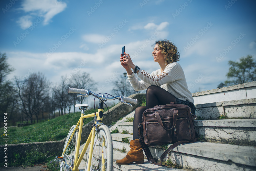 stylish woman with a bicycle using cell phone