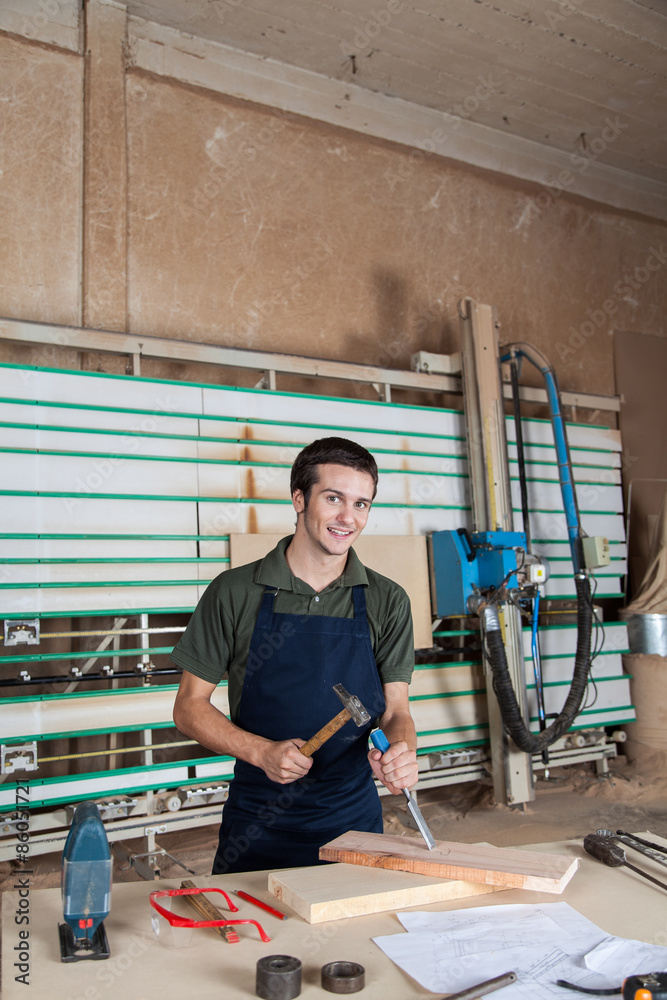 Smiling carpenter working with a chisel