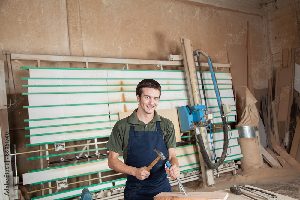 Smiling carpenter working with a chisel