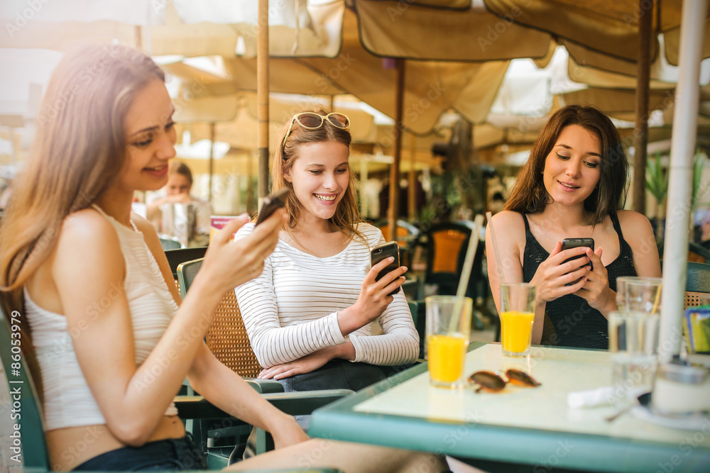 Three girl at the cafe sending text messages Three girl at the cafe sending text messages
