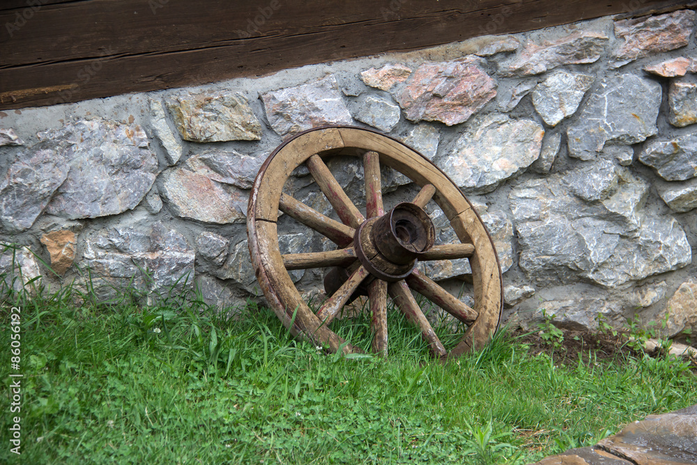 Fototapeta premium Old Wagon Wheel / Old Wagon Wheel against an Old Historic House Wall.