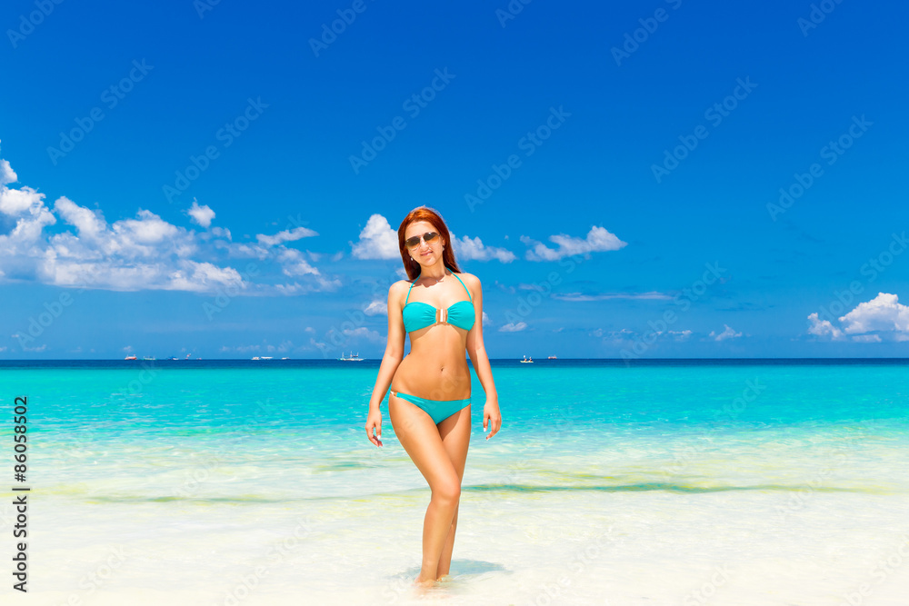 Beautiful young girl in turquoise bikini on a tropical beach. Bl